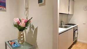 A modern kitchen with white cabinets, a stainless steel sink, and a built-in oven. - JOIVY Apartment, Window to the Vertical Forest (Milan)