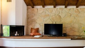 A stone wall, a flat-screen TV, a fireplace, and a bench. - JOIVY Attic on the Lake (Argegno)
