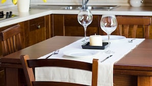 A dining table set with white plates, cutlery, and two wine glasses, with a candle and a small tray on the table. - JOIVY Attic on the Lake (Argegno)