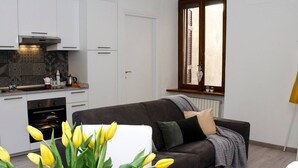 Una cocina moderna con armarios blancos, horno integrado y ventana con vistas al exterior.