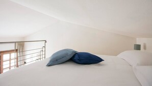 A bedroom with a bed, two pillows, a nightstand with a lamp, a window with curtains, and a balcony railing. - JOIVY Green Terraced House (Pisa)