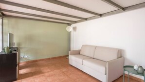 A room with a white sofa, a small table with a vase, and a desk with a cactus and a lamp. - JOIVY Green Terraced House (Pisa)