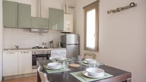 A compact kitchen with a dining area, equipped with basic appliances and a window for natural light. - JOIVY Green Terraced House (Pisa)