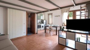 A spacious living area with a kitchen, dining table, and a flat-screen TV. - JOIVY Green Terraced House (Pisa)