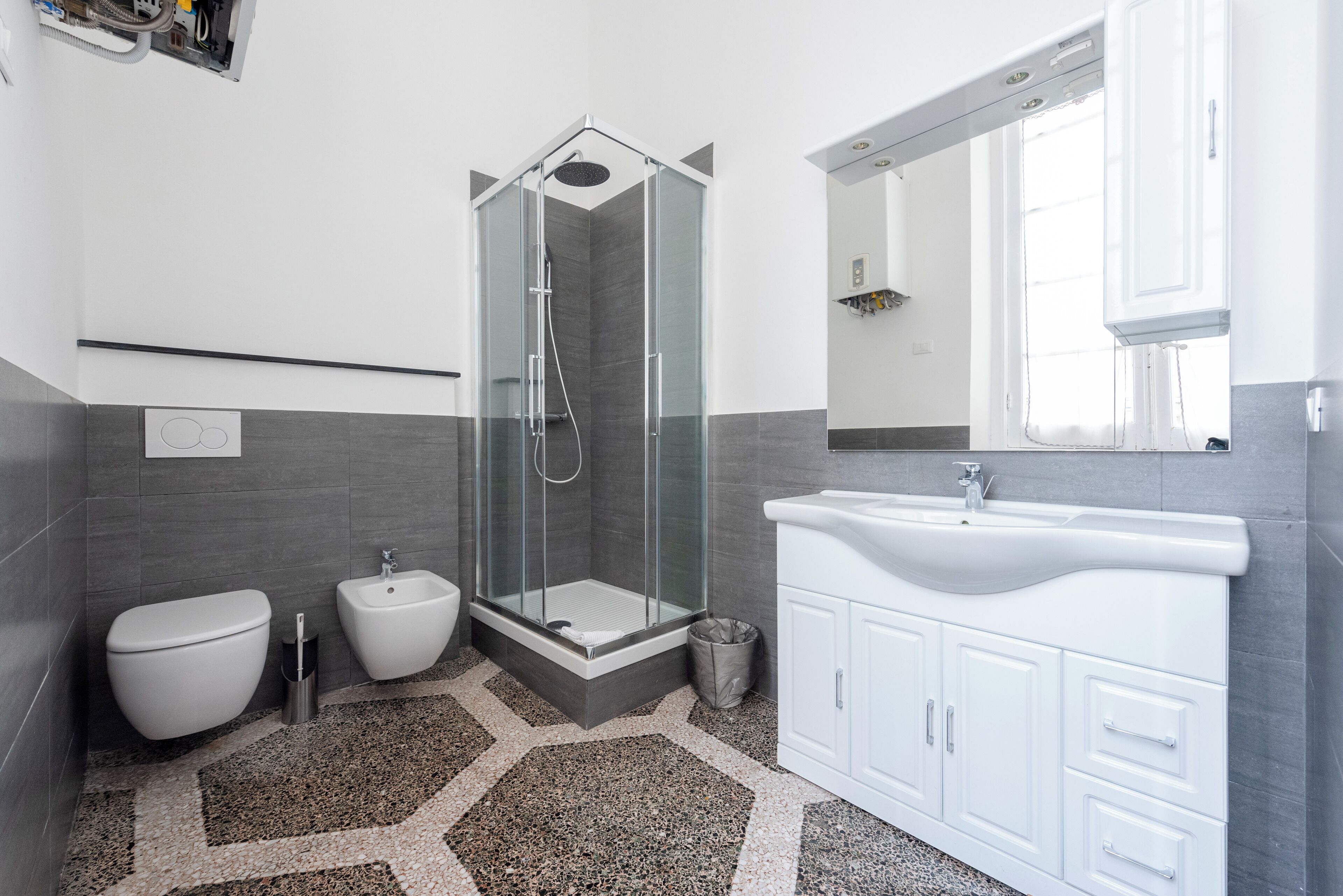A modern bathroom with a glass-enclosed shower, a white sink, and a bidet.