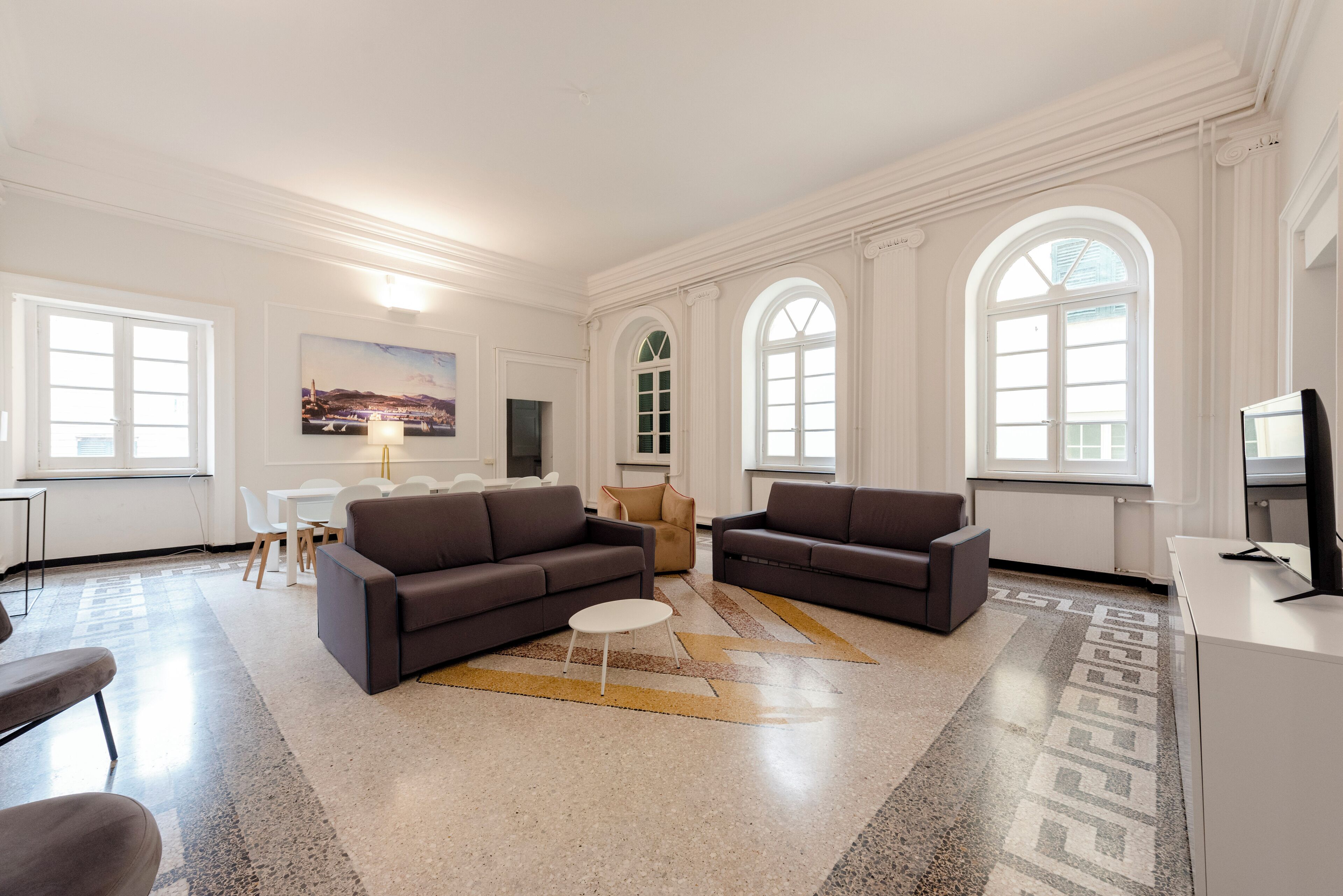 A spacious living room with two sofas, a coffee table, and a dining area with chairs and a table.