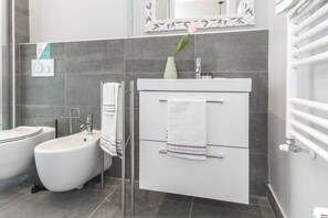 A modern bathroom with a bidet, a sink, and a mirror above the vanity.