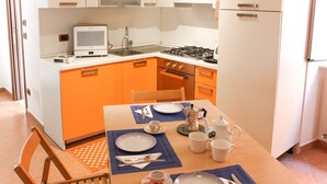 A compact kitchen with a stove, sink, and a small television. - JOIVY Riva Trigoso Casetta nel Borgo (Sestri Levante)
