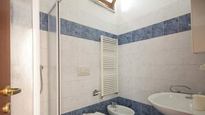 A bathroom with a shower, toilet, bidet, and sink. - JOIVY Red Terraced Apartment (Pisa)