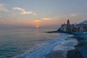Un paysage côtier avec un ensemble de bâtiments au bord de la mer, au coucher du soleil.