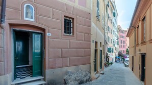 A narrow street with buildings on either side, featuring a green door and a small window on the pink building. - JOIVY Porto Bello a Camogli (Camogli)