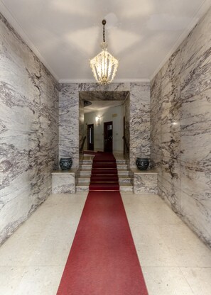 Stunning entrance hall with a grand staircase, marble floor, and elegant chandelier.