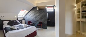 Relax in a spacious room with a large bed, a small table, and a sofa, featuring a minimalist design with a unique wall panel.