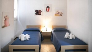 A hotel room with two beds, a nightstand, and wall art depicting dogs and cats. - JOIVY Villa Il Glicine sul Mare (Pietrasanta)