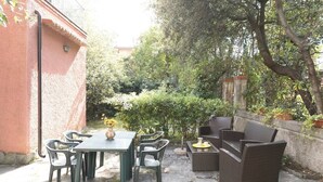 A patio with a table and chairs, a small sofa, and a potted plant. - JOIVY Villa Il Glicine sul Mare (Pietrasanta)