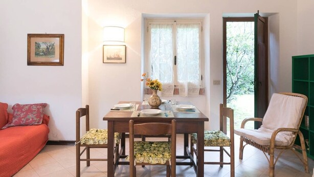 A dining area with a table set for two, a sofa, and a chair. - JOIVY Villa Il Glicine sul Mare (Pietrasanta)