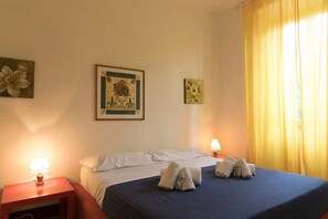 Une chambre d’hôtel avec un lit, deux lampes de chevet et deux tableaux au mur.