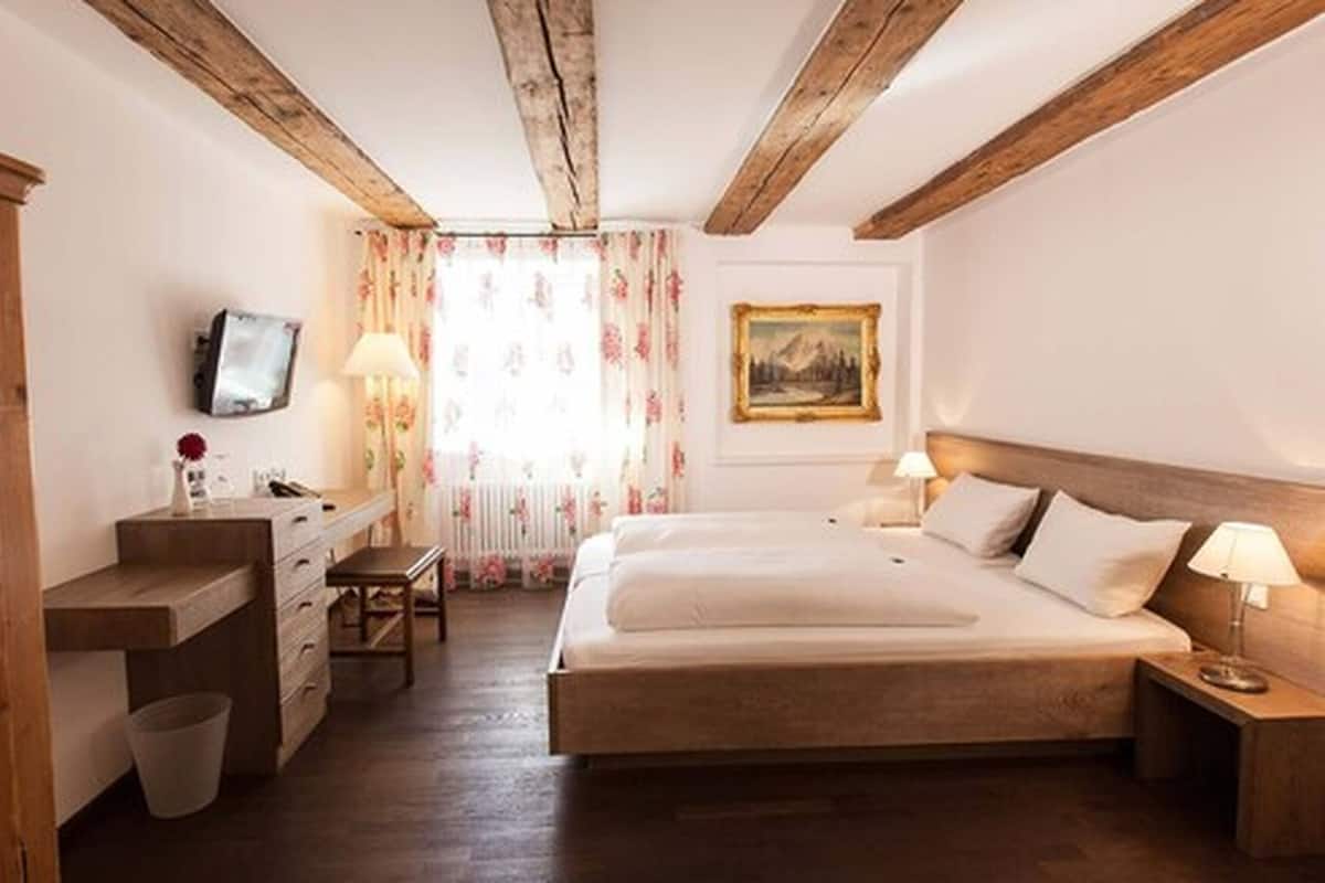 Une chambre à coucher avec un lit en bois, des tables de chevet, un bureau, une chaise et un téléviseur.