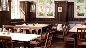 A restaurant with wooden booths, tables, and hanging light fixtures. - Hotel & Brauereigasthof Kapplerbräu (Altomunster)