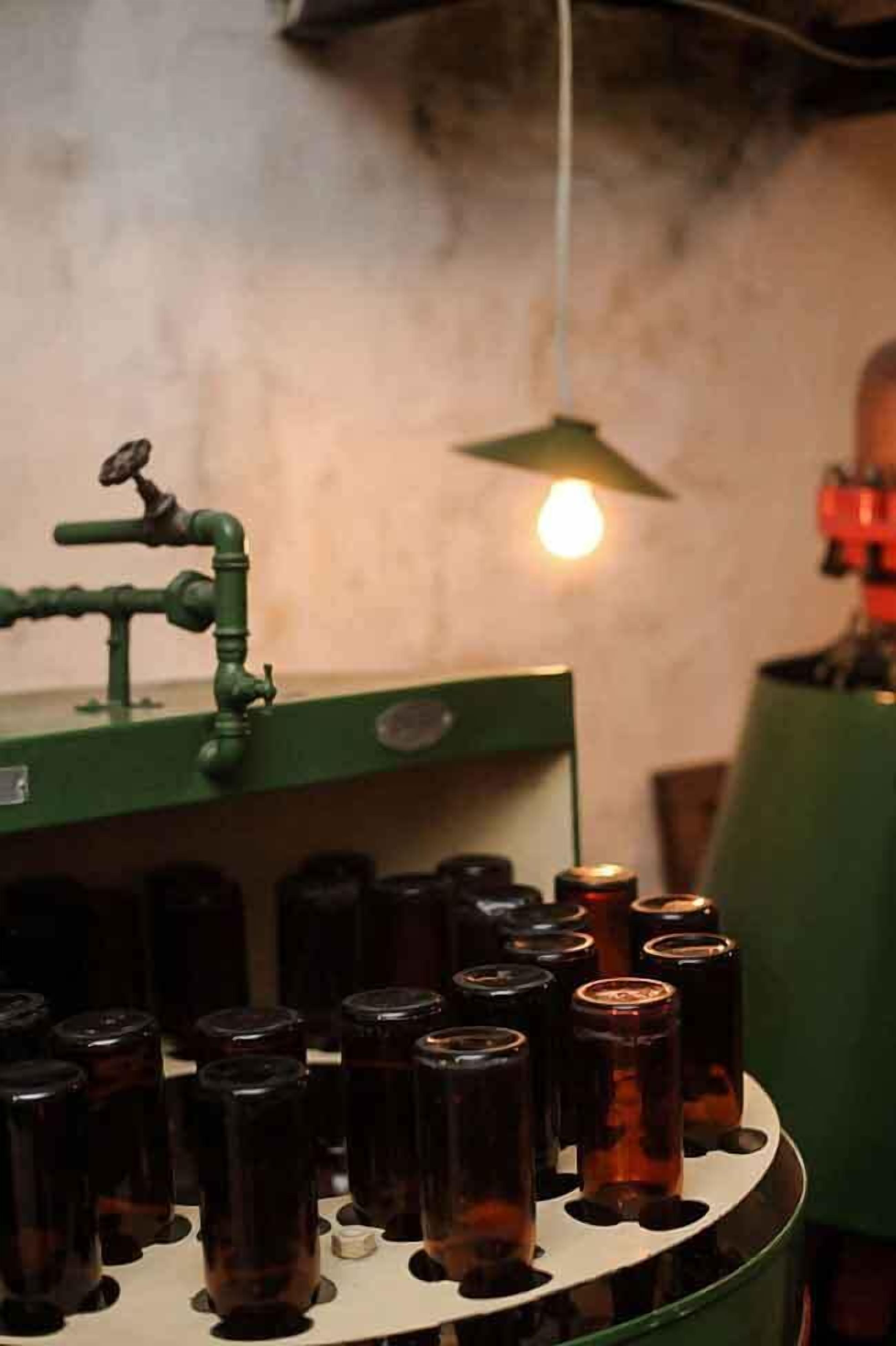 Una habitación con una mesa verde que sostiene varias botellas marrones, una lámpara verde y un grifo de agua.
