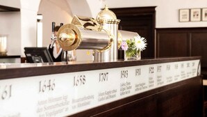 A reception desk with a brass cannon, a vase with flowers, and a plaque listing years and names. - Hotel & Brauereigasthof Kapplerbräu (Altomunster)