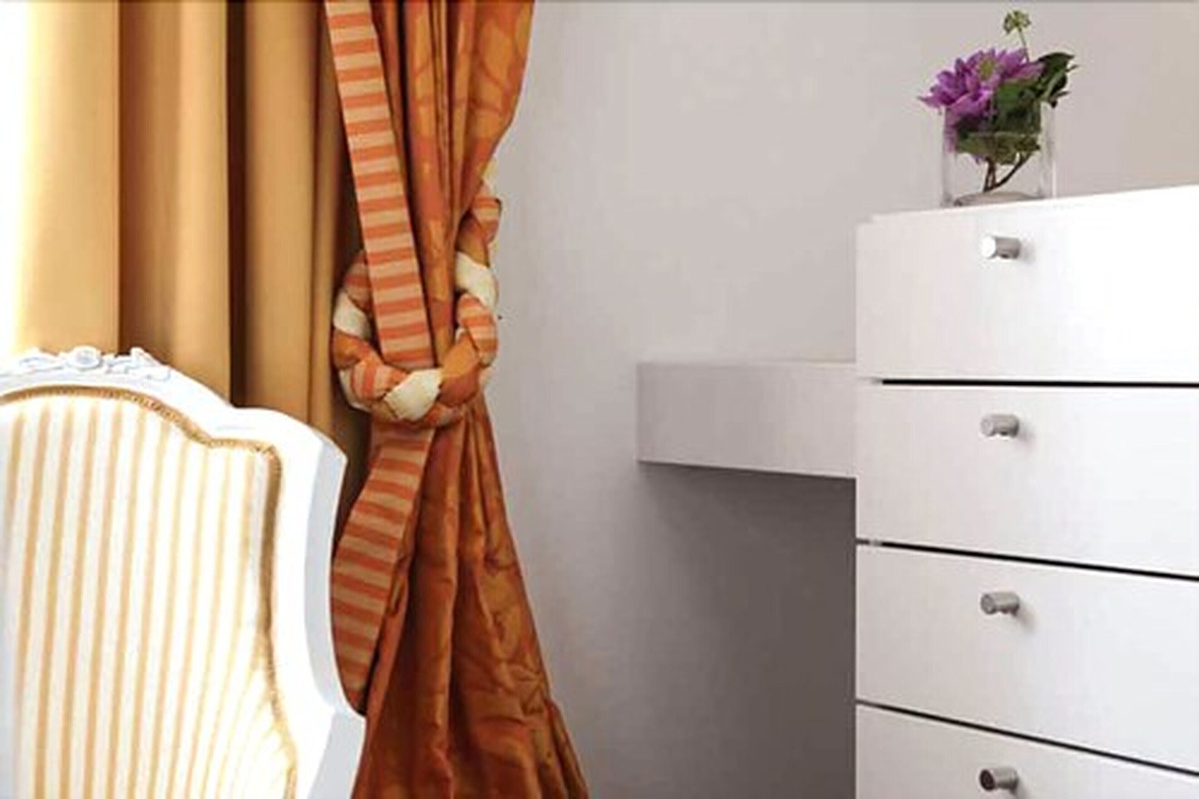 A bathroom with a white cabinet, a striped towel, and a vase with flowers on the counter.