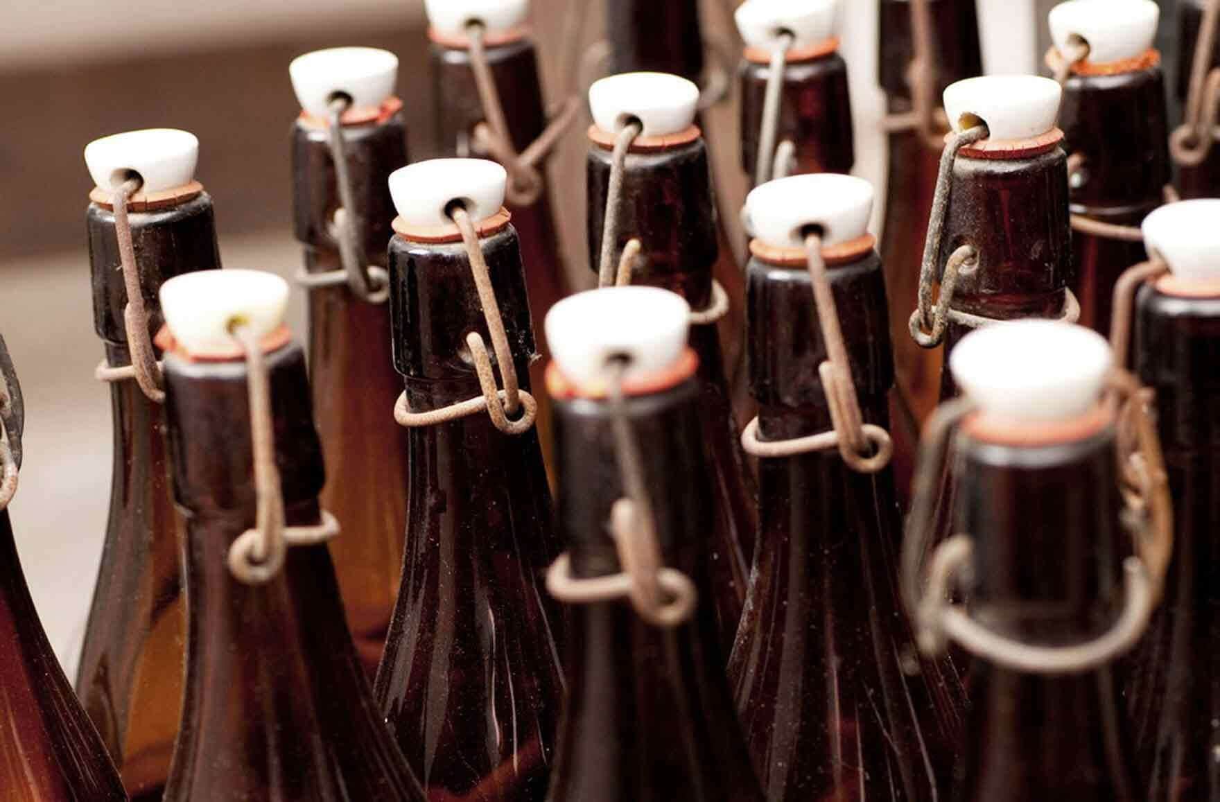 A collection of dark glass bottles with white caps and metal clasps, likely containing beverages.