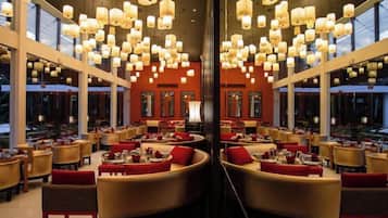 Un restaurant doté de nombreuses tables et chaises, de grandes fenêtres et de luminaires suspendus.
