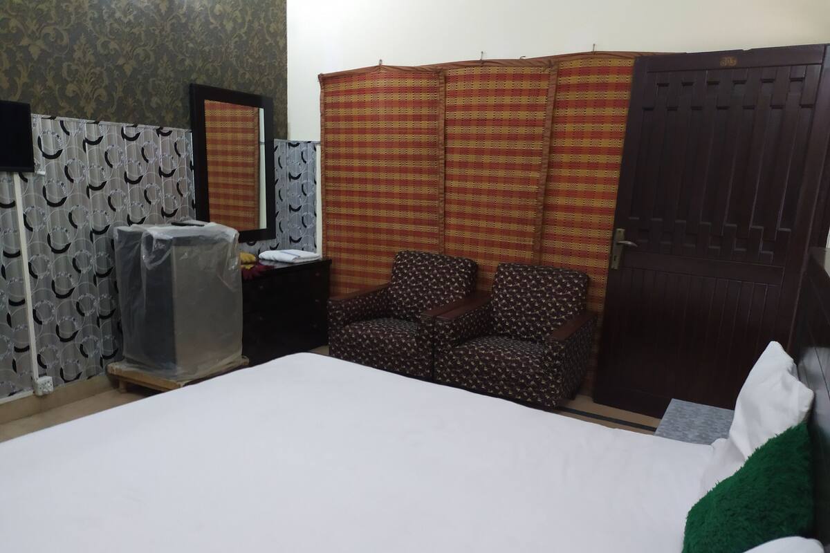 Une chambre à coucher avec un lit, une chaise, une armoire, un miroir et une petite table.