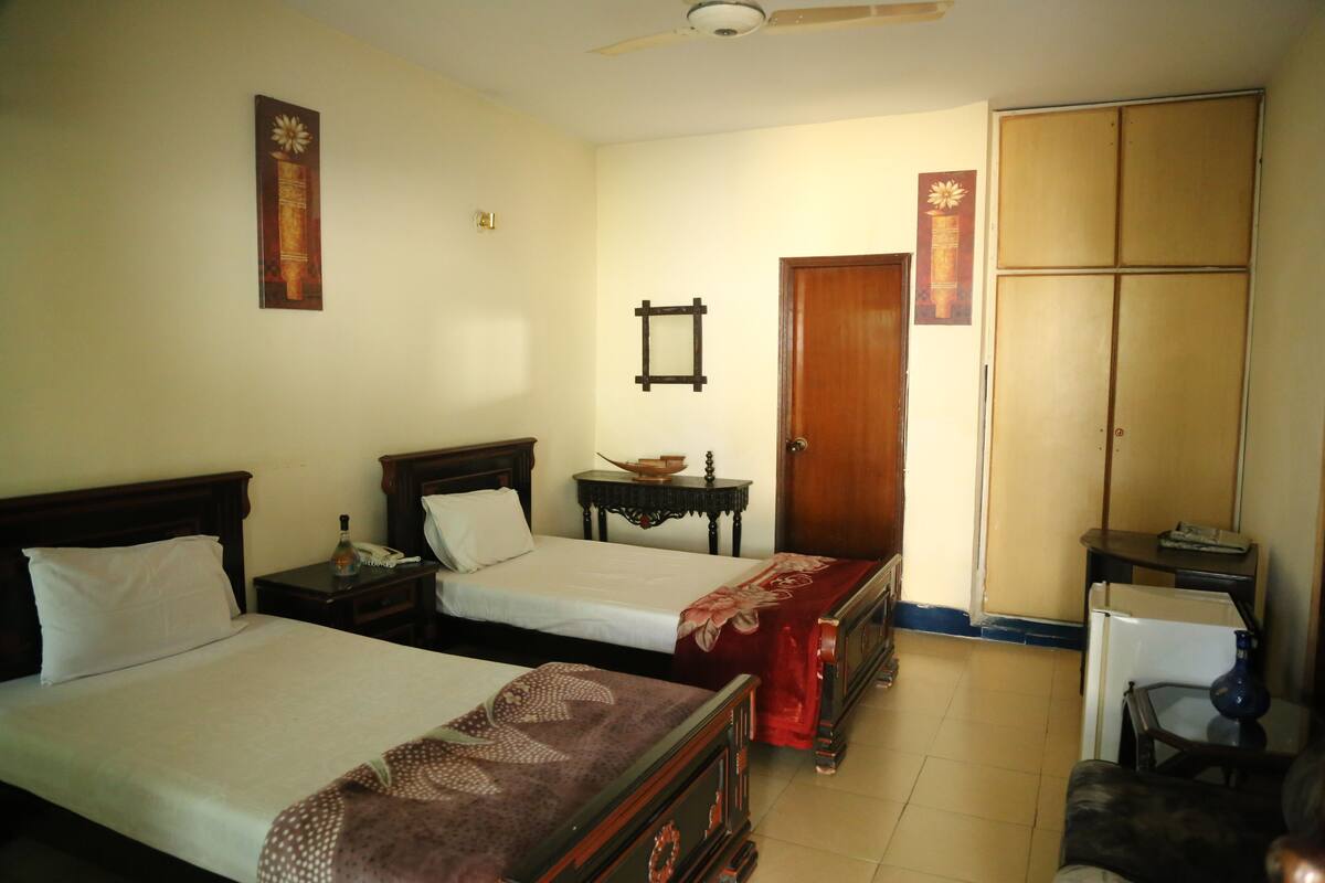 Une chambre d’hôtel avec deux lits, une armoire, un bureau et une chaise.