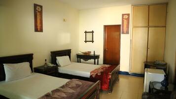 A hotel room with two beds, a wardrobe, a desk, and a chair.