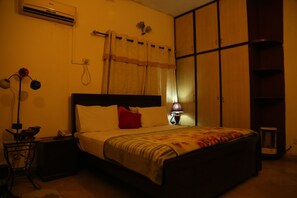 A bedroom with a bed, bedside table, lamp, and wardrobe. - Hotel Sweet Inn (Lahore)