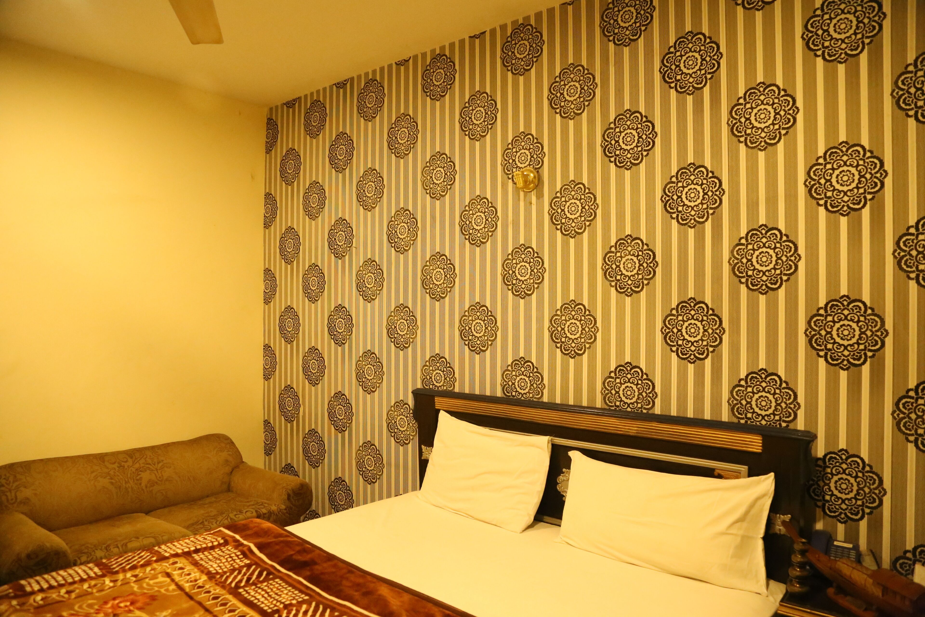 Een hotelkamer met een bed, een slaapbank en behang met een patroon.