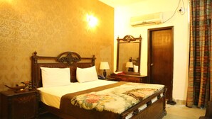 A traditional bedroom with a wooden bed, a nightstand, a mirror, and an air conditioning unit on the wall. - Hotel Sweet Inn (Lahore)