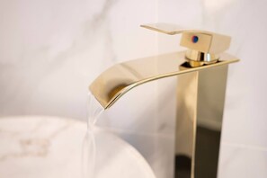 Ein moderner, goldfarbener Wasserhahn mit einhebeliger Armatur, aus dem Wasser fließt.