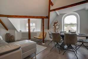 Een eetgedeelte met een tafel voor vier personen, een leren bank en een raam met uitzicht.