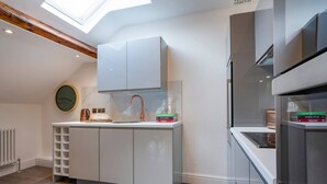 A modern kitchen with a skylight, white cabinetry, and a built-in oven. - 3 Bedroom Apartment in Windermere - Bathtub (Windermere)