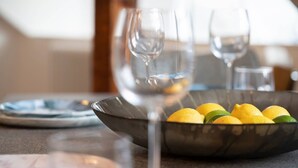 A dining table with a bowl of lemons and two empty wine glasses. - 3 Bedroom Apartment in Windermere - Bathtub (Windermere)