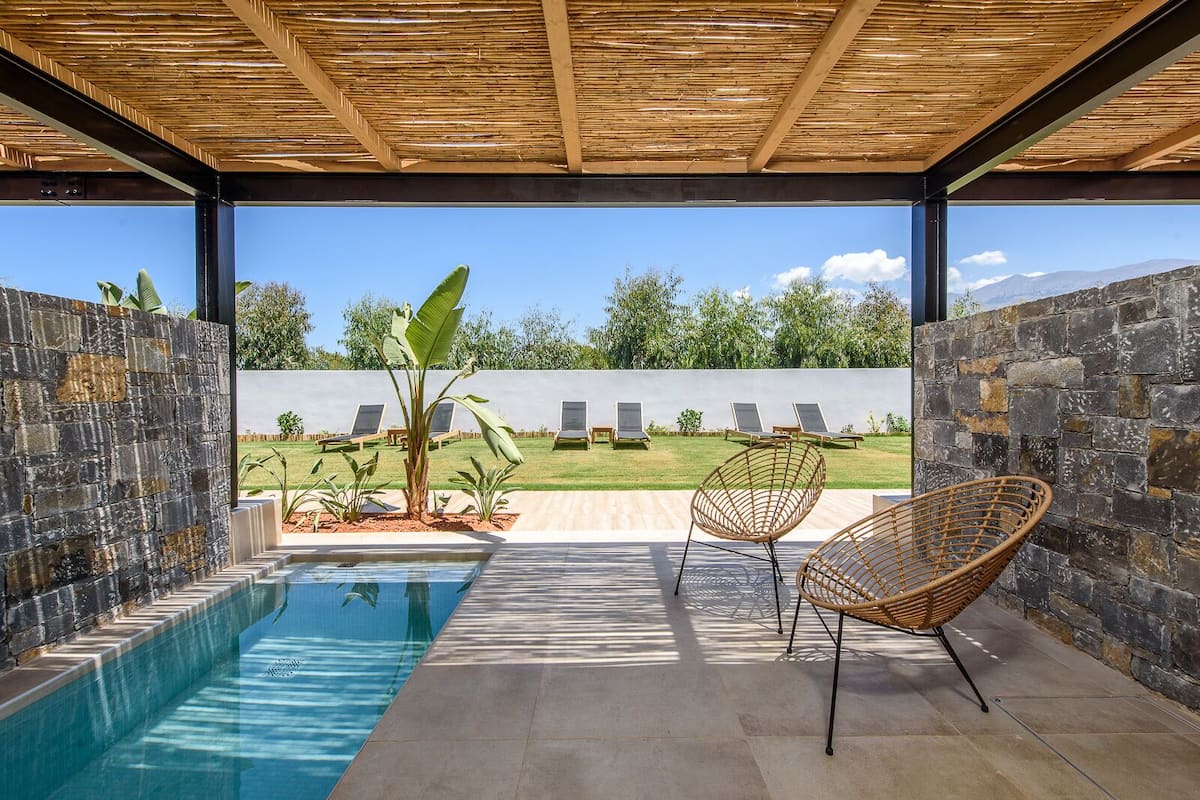 A pool area with a view of a garden and lounge chairs.