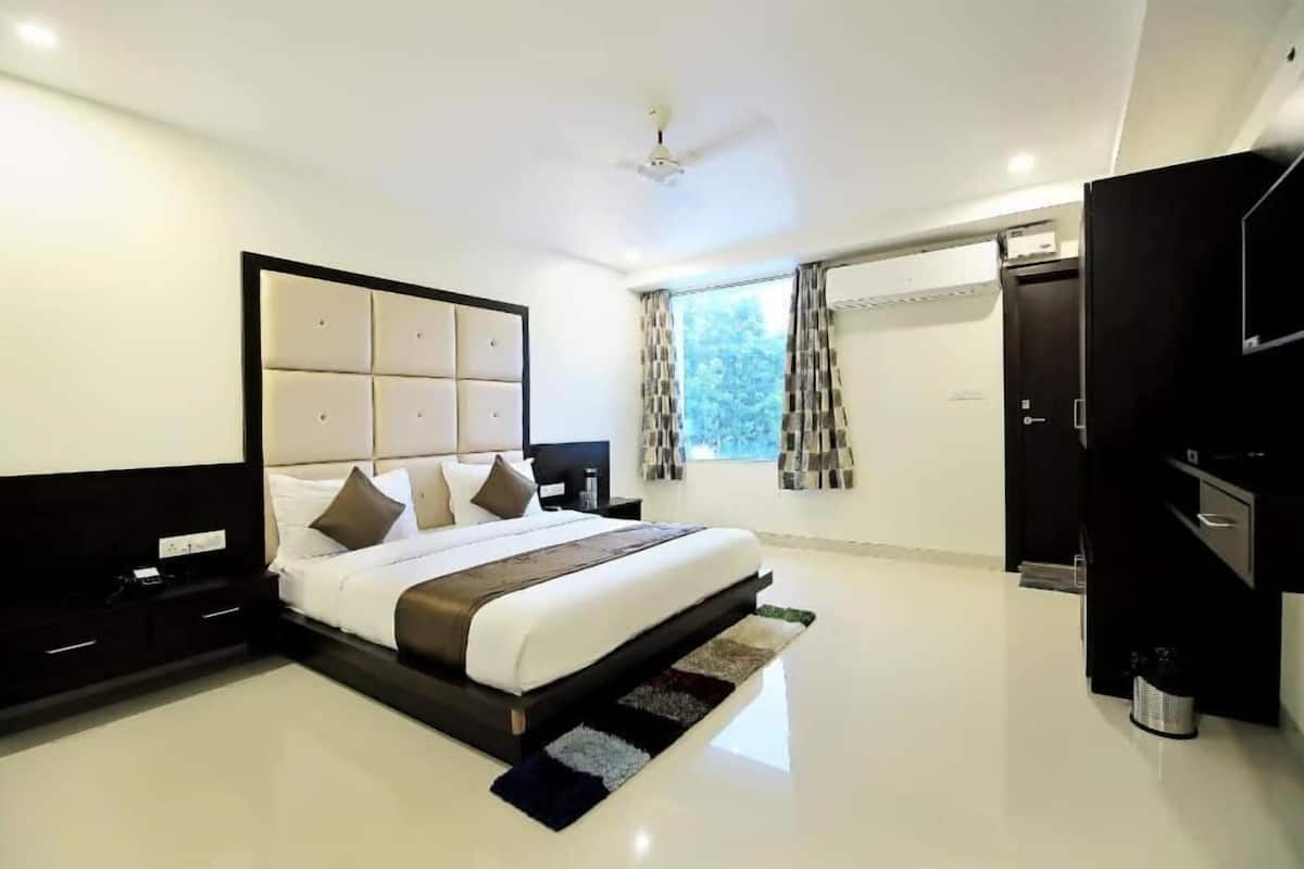 A modern bedroom with a large bed, a TV, and a wardrobe.