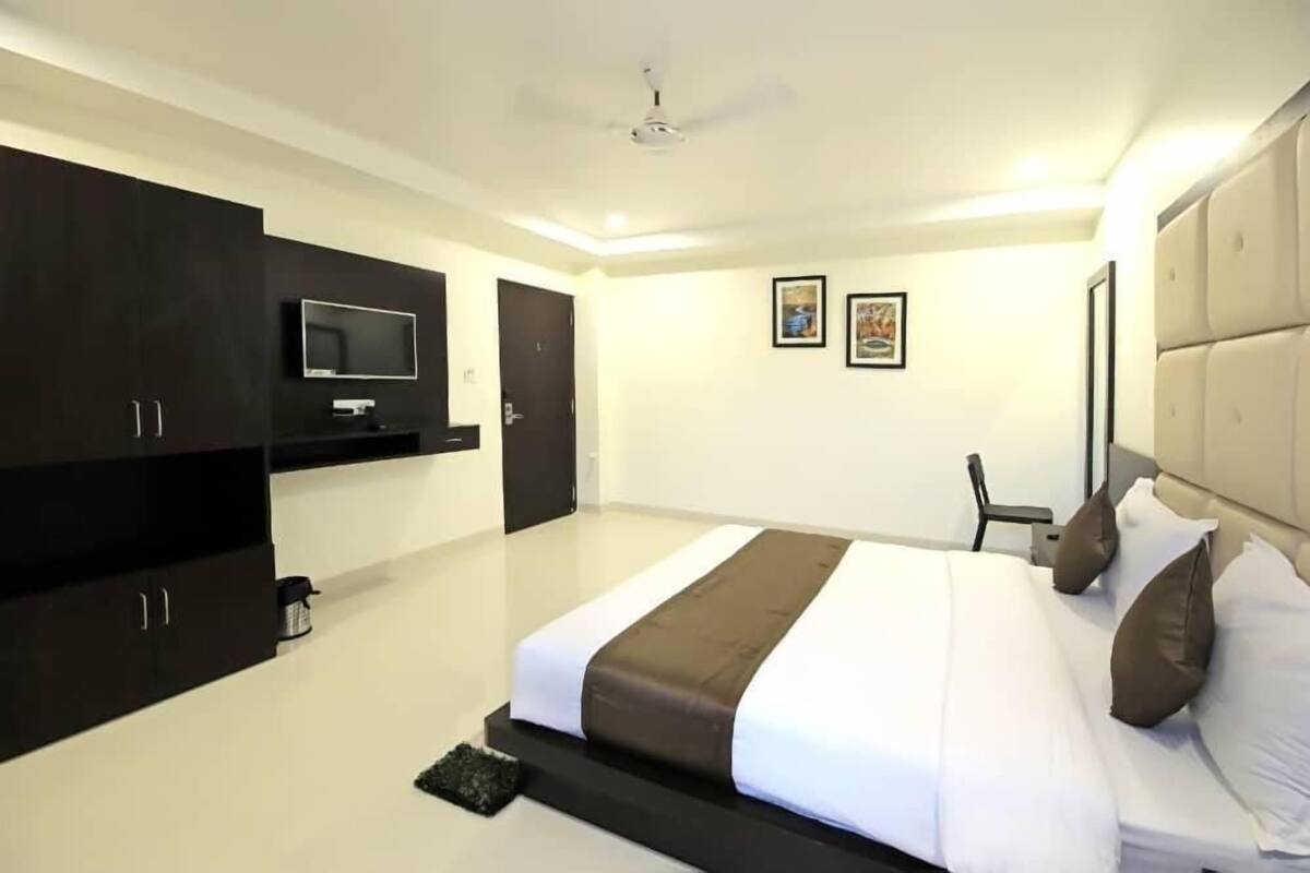 A modern hotel room with a large bed, a flat-screen TV mounted on the wall, and a ceiling fan.