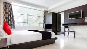A modern bedroom with a large bed, a TV mounted on the wall, and a view of a staircase outside. - Dasmaya Resort (Udaipur)