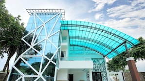 A modern building with a glass facade and a distinctive white geometric structure in front. - Dasmaya Resort (Udaipur)