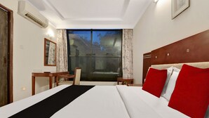 Habitación de hotel con una cama grande, un escritorio, una silla y vistas al exterior a través de un ventanal amplio.