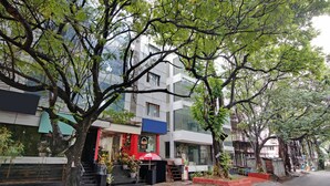 Un edificio moderno con entrada roja, ventanas grandes y una escalera que lleva a la entrada.