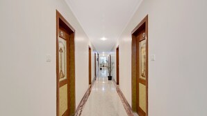 Un pasillo largo y estrecho con puertas de madera y suelo de mármol.