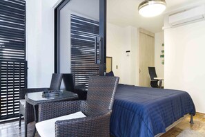 A hotel room with a bed, a small table, and a chair.
