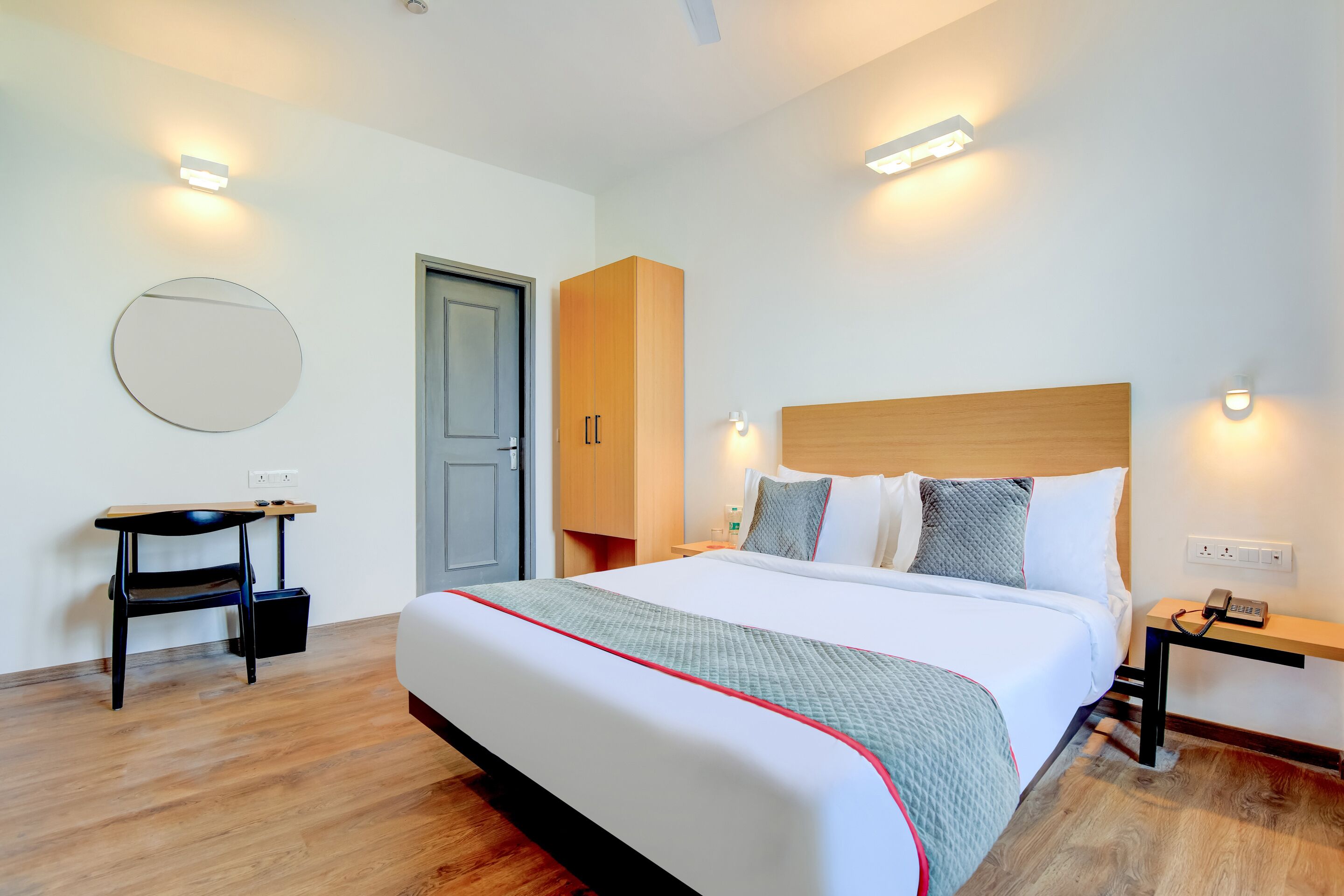 Una habitación de hotel moderna con una cama grande, mesitas de noche, un escritorio y un armario.