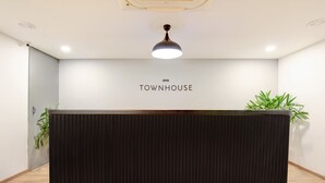 A reception desk with a sign reading "OYO TOWNHOUSE" and two potted plants on either side. - Hotel Aravali Inn & Banquet Hall (Faridabad)