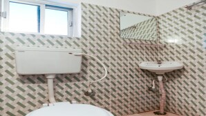 A bathroom with a toilet, sink, and a window.